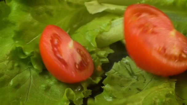 Vídeo de la caída de medio tomate sobre lechuga verde — Vídeo de stock