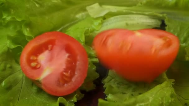 Video van vallende half rode tomaat op sla — Stockvideo