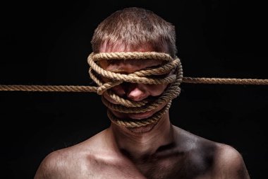 Yüzünde ip olan bağlanmış bir adamın fotoğrafı.