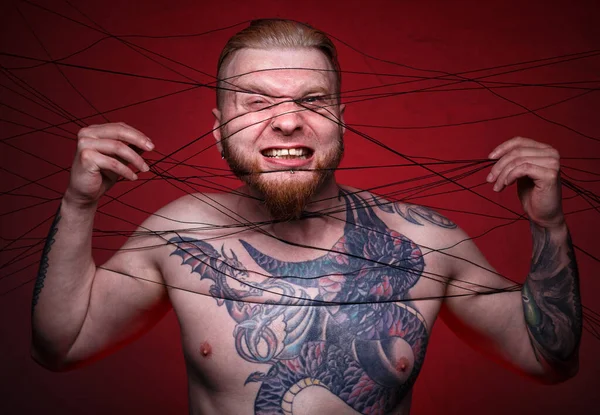 Photo of tangled in black threads bearded blond man — Stock Photo, Image