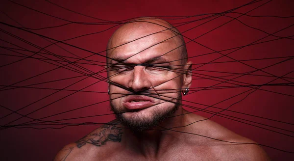 Photo of tangled in threads bald man on red background — Stock Photo, Image