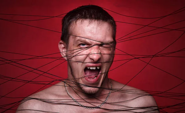 Foto av skrikande galen man i svarta trådar på röd bakgrund — Stockfoto