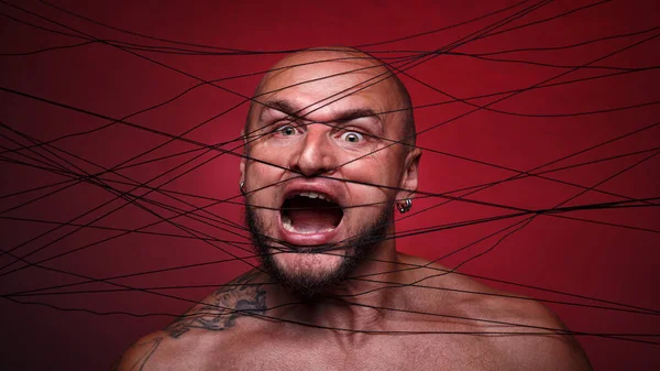 Image of tangled in threads bald screaming man