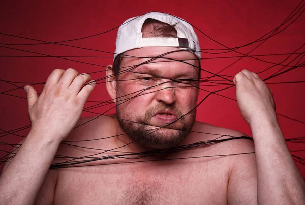 Image of tangled in black threads fat man on red background — Stock Photo, Image