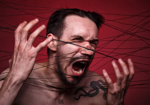 Photo of screaming tangled in black threads brunette man — Stock Photo, Image