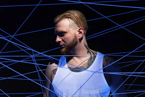 Uomo tatuato aggrovigliato in fili in luce al neon — Foto Stock