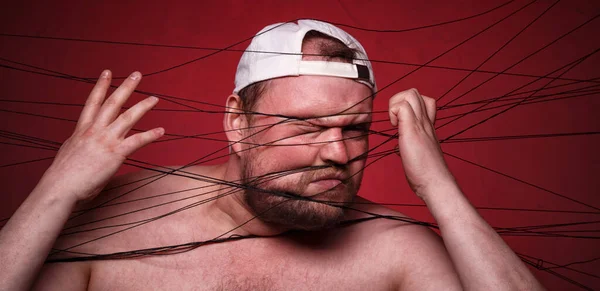 Fat man tangled in black threads on red background — Stock Photo, Image