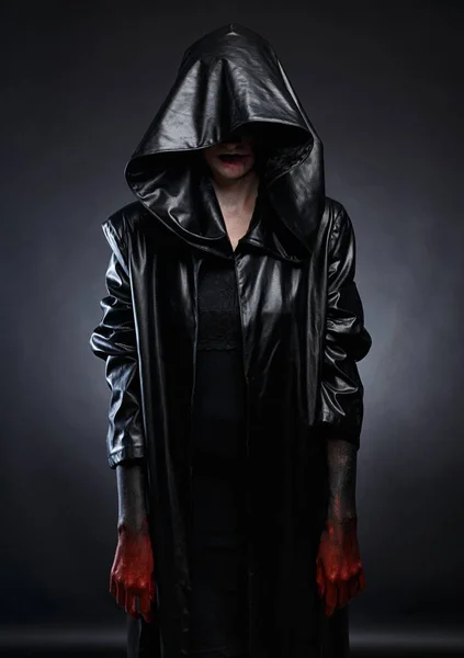 Foto de mulher em capuz de couro preto com mãos vermelhas — Fotografia de Stock
