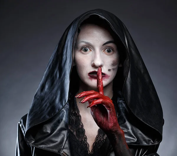 Photo of woman in black hood with red hands showing shh — Stock Photo, Image