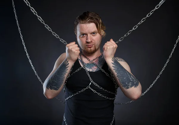 Изображение татуированного жестокого человека, закованного в цепи — стоковое фото