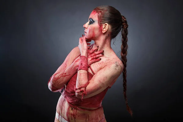 Жінка у фальшивій крові на сірому фоні — стокове фото