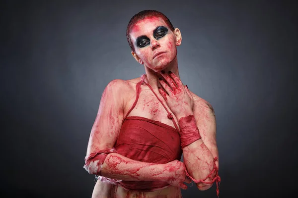 Ужасная фотография девушки в фальшивой крови на сером фоне — стоковое фото