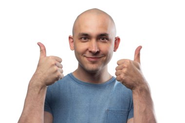 Mavi tişörtlü başparmağını gösteren kel bir genç resmi.