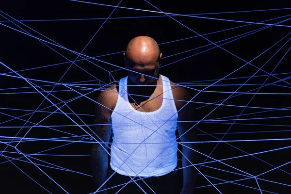 Photo of bald man tangled in white threads with head down in ultraviolet — Stock Photo, Image