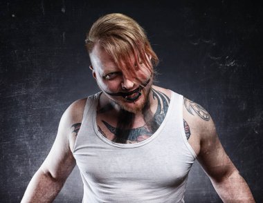 Korku makyajlı, dövmeli, korkunç, çılgın bir adamın resmi.