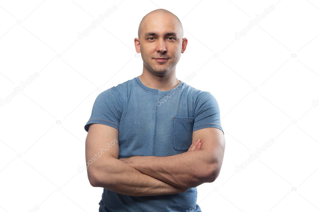 Image of young bald man with arms crossed in blue tee shirt