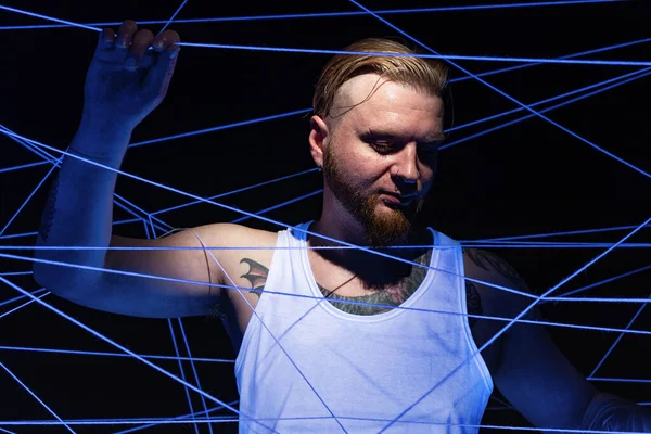 Imagem do homem tatuado emaranhado em fios em luz de néon — Fotografia de Stock
