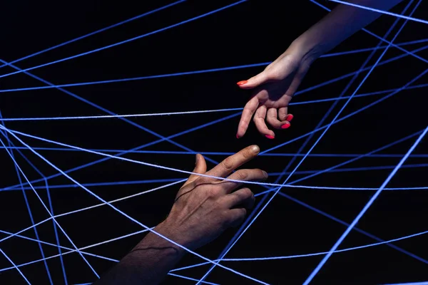 Male and female hand among threads in neon light — Stock Photo, Image
