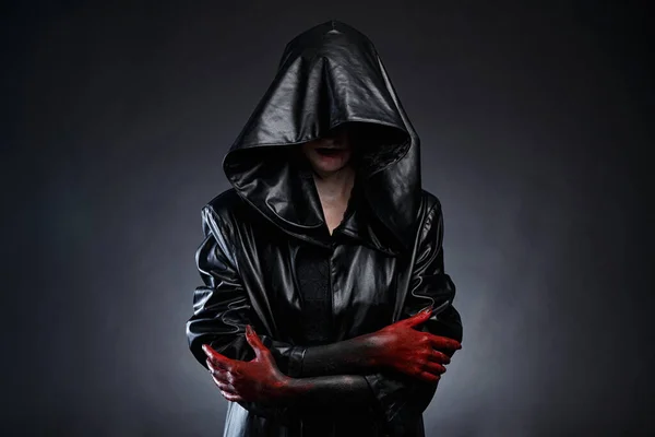 Imagen de mujer en capucha de cuero negro con manos rojas —  Fotos de Stock