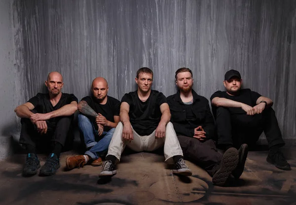 Изображение группы мужчин, сидящих на грязном полу Стоковое Фото