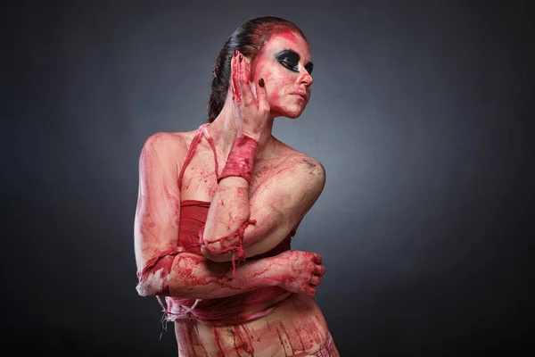 Изображение страшной девушки в фальшивой крови на сером фоне — стоковое фото