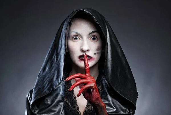 Portrait de femme en capuche noire avec les mains rouges montrant shh — Photo