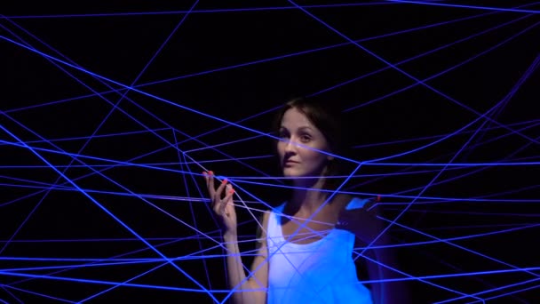 Video van vrouw verstrengeld in witte draden in ultraviolet — Stockvideo