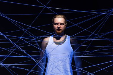 Beyaz iplikler içinde neon ışığa dolanmış sakallı bir adam resmi