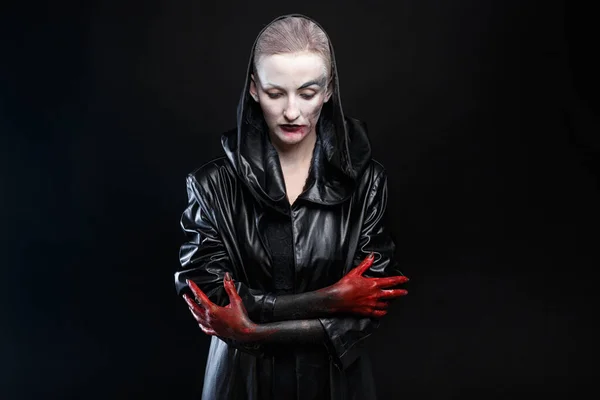 Bild av kvinna i svart läder regnrock med röda händer — Stockfoto
