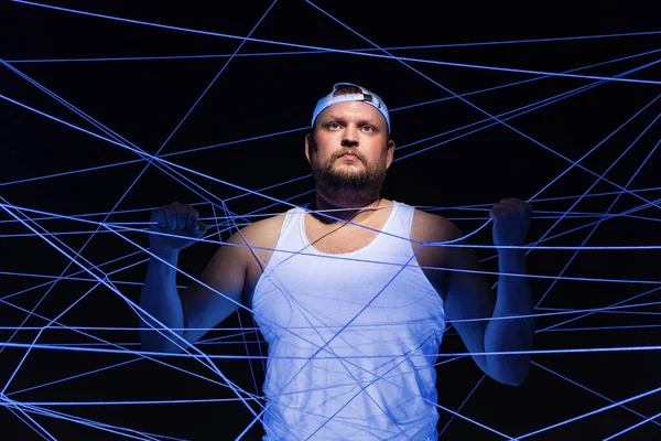 Imagem de homem gordo emaranhado em fios brancos em ultravioleta — Fotografia de Stock
