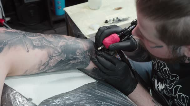 Стрельба татуировщика, делающего татуировку на локте в салоне — стоковое видео