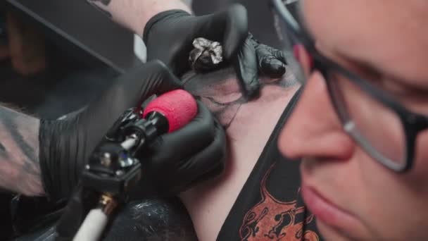 Стрельба мастера, делающего черную татуировку на плече — стоковое видео