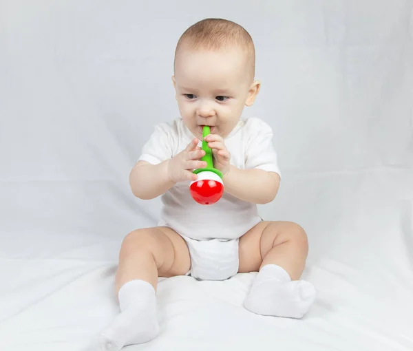 Eight month old baby with rattle in mouth — Stock Photo, Image
