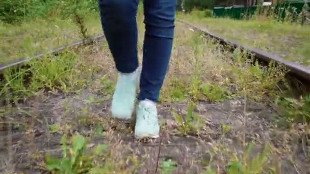 Видео девушки, идущей по заброшенной железной дороге летом — стоковое видео