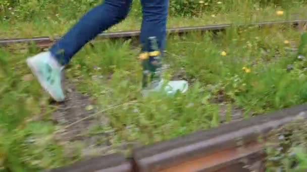 Девушка ходит по заброшенной железной дороге летом — стоковое видео