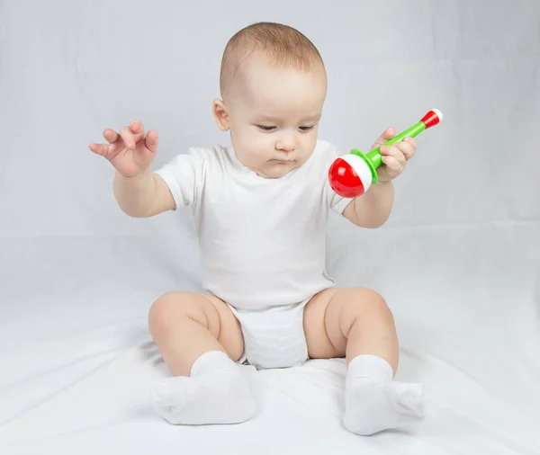Imagem de um bebê de oito meses com chocalho na boca — Fotografia de Stock