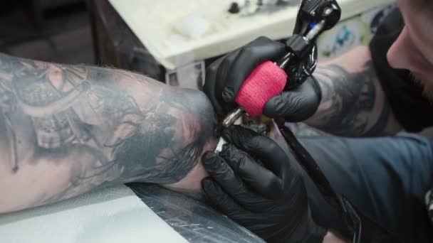 Bilder på tatuerare som tatuerar sig på armbågen i salongen, ovanifrån — Stockvideo