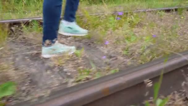 Beelden van een meisje dat in de zomer op een verlaten spoorweg loopt — Stockvideo