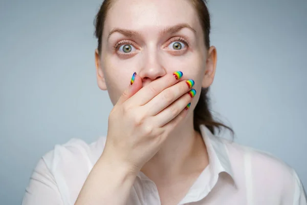 Foto de niña con manicura arco iris que cubre su boca —  Fotos de Stock