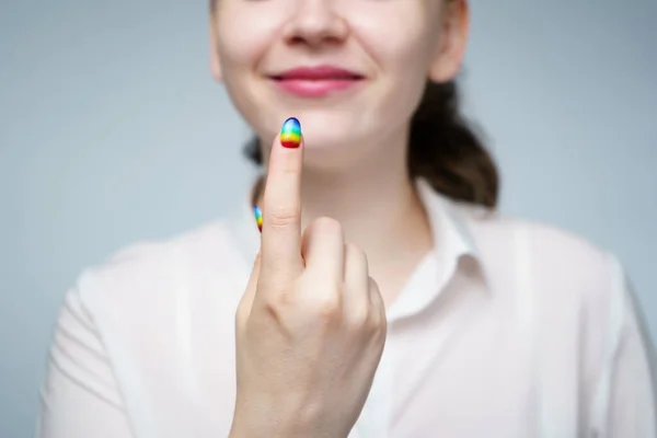 Foto de mujer con el dedo de señas de manicura arco iris —  Fotos de Stock