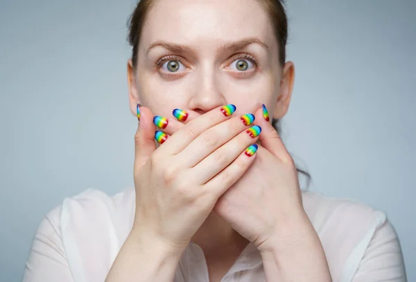 Imagen de niña con manicura de arco iris cubriendo su boca —  Fotos de Stock