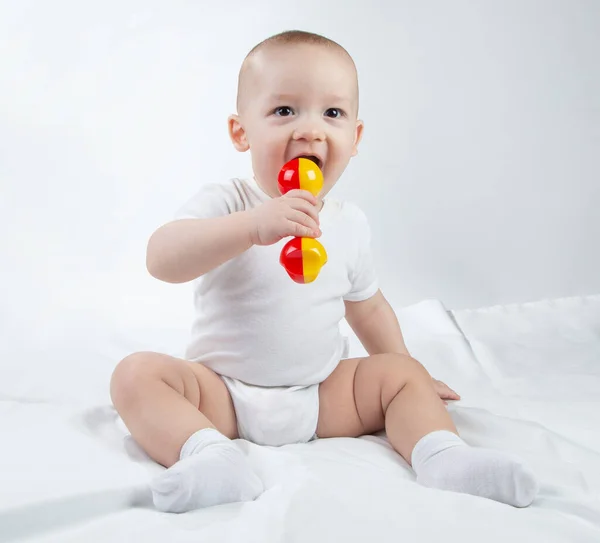 Photo of a nine-month-old baby with rattle in the mouth — Stock Photo, Image