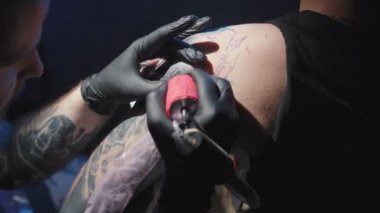 Kuaförde bir adamın omzuna dövme yaptıran bir dövmeciyi vurmak.