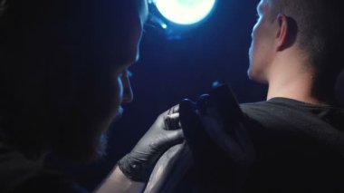 Profesyonel bir adamın omzunda dövme yaptırıyor.