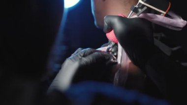 Genç bir adamın omzuna dövme yaptıran bir dövmenin videosu.