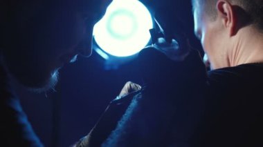 Genç bir adamın omzuna dövme yaptıran usta bir dövmenin çekimi.