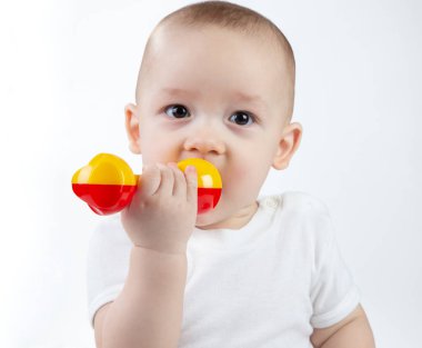 Beyaz arka planda çıngırağı olan 9 aylık bir bebeğin portresi.