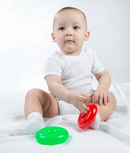 Photo of a sitting nine-month-old baby with bright toys — Stock Photo, Image