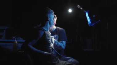 Dövmeci bir erkeğin omzuna dövme yapıyor.