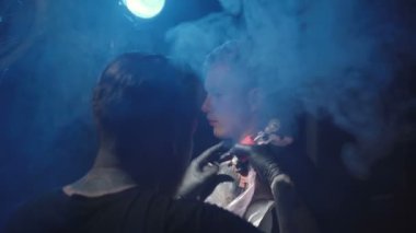 Usta kuaförde bir adamın omzuna dövme yaptırıyor.